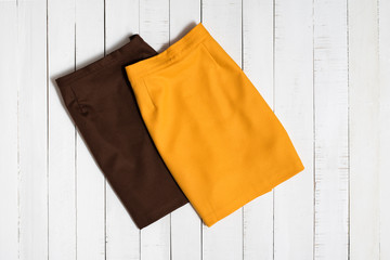 Fashion clothes. Brown and orange mini skirts on white wooden floor planks