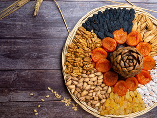 mix of nuts as walnuts, almond, cedar, pistachios, and dried apricots, blue and yellow raisin wheat cereal on wooden background