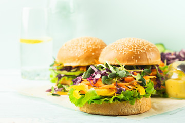 Appetizing burger from fresh sesame buns and raw vegetables and young sprouts blue light background.Healthy nutrition