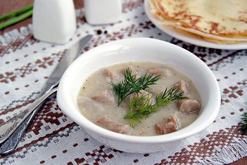 Machanka, thick sauce on meat broth with homemade pork sausages in a white bowl. Served with thin wheat pancakes. Belarusian cuisine