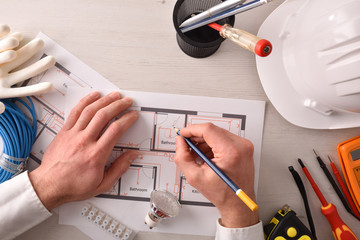 Technical engineer in electricity writing in an electrical plan top