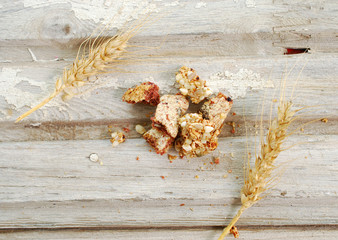 pieces of a sweet cereal bar and cereal ears on an old wood background