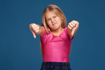 Portrait of emotional expressive little girl on blue background