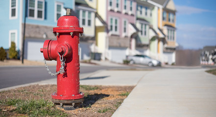 Fototapeta na wymiar Close up bokeh shot of a bright red fire hydrant with brightly colored townhouses in the background.