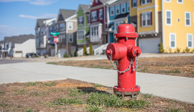 Close up bokeh shot of a bright red fire hydrant with brightly colored townhouses in the background.