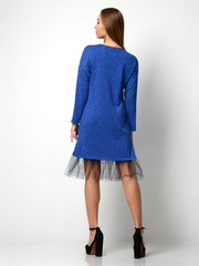 Young beautiful woman posing in new design casual blue winter dress back view full body on grey
