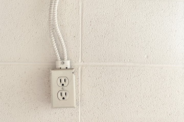 Old rustic North American electrical outlet on a white brick wall