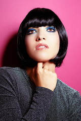 girl portrait with black wig and blue make up on an fuchsia background