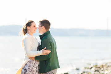 girl and guy are hugging and looking at each other on the bank o