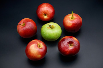 Five red apples and green on black background