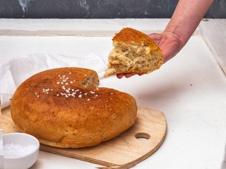 Freshly baked homemade wholegrain flour bread cut, the girl s hand treats a piece of sliced bread