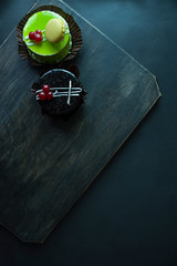 Delicious cake. A small green-coated pistachio cake and chocolate cake on a black background. View from above.