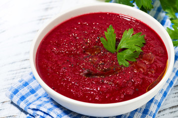 cold beet soup in a bowl on white background, top view closeup