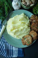 Pork cutlets with mashed potatoes, greens and fresh vegetables on a black background. View from above.