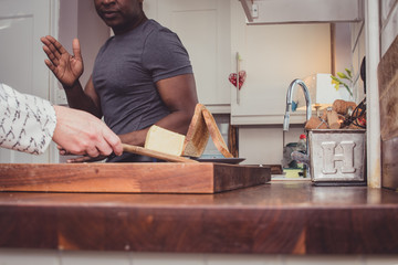 A gay couple sharing stories from their day at work over a slice of toast and a cup of tea and coffee in the evening. 