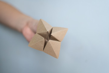 Woman's hands holding a paper fortune teller on blue background