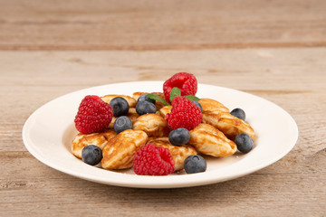 Pancakes, poffertjes with blueberries, raspberries and sugar