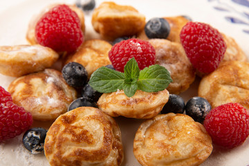Pancakes, poffertjes with blueberries, raspberries and sugar