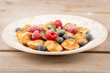 pancakes, poffertjes with blueberries, raspberries and sugar