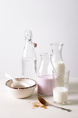 Milk shake glass with bottle strawberry yogurt, cocoa, bottle of water on white wood background