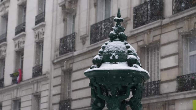 Beautiful fountain statue being covered in snow in Paris, France