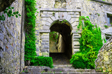 Stone walls, arches, stairs, lamp and green dangling plants of ancient Castello Doria castle tower in Portovenere town, La Spezia, Liguria, Italy