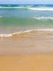 Sea salty pure blue waves roll on the sand of the local beach. Low waves on a sunny day.