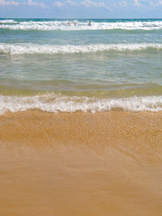 Sea salty pure blue waves roll on the sand of the local beach. Low waves on a sunny day.