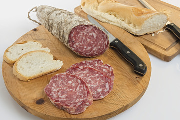 salame tagliato su tagliere di legno con pane e coltello