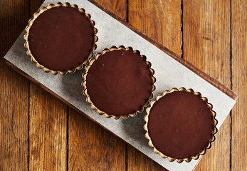 Three chocolate tarts sitting on a cafe serving board