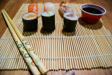 Sushi rolls, makis and nigiris with soy sauce on a traditional japanese carpet with chopsticks
