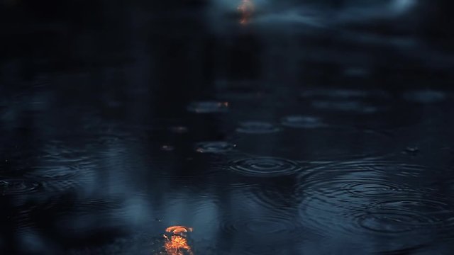 Drizzle raindrop ripples in a pond at night in slow motion