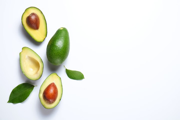 Minimal composition with whole and halved nutrient dense avocado fruit slices full of heart healthy monounsaturated fat on gray glass table top. Close up, copy space, top view, background.