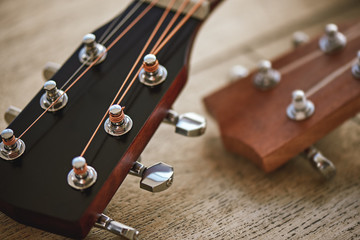 Sound adjusting. Close up photo of guitar necks with tuning keys for adjusting strings against wooden background.