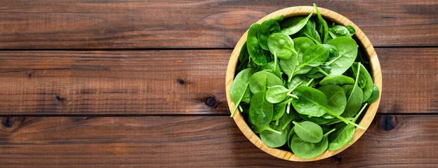 Fresh spinach leaves on wooden background. Healthy vegan food. Top view. Banner