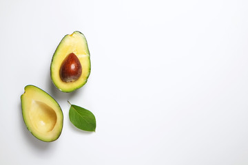 Minimal composition with leaf and halved nutrient dense avocado fruit slices full of heart healthy monounsaturated fat on isolated white background with copy space for text. Close up, top view.