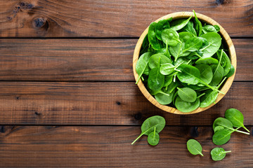Fresh spinach leaves on wooden background. Healthy vegan food. Top view.