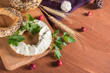 Whole grain bagels with cream cheese on wooden board