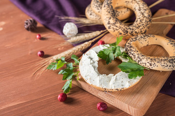 Obraz na płótnie Canvas Whole grain bagels with cream cheese on wooden board