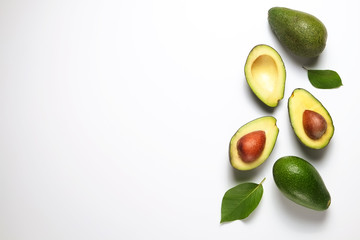 Minimal composition with whole and halved nutrient dense avocado fruit slices full of heart healthy monounsaturated fat on gray glass table top. Close up, copy space, top view, background.