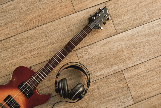 Guitar recording. An electric guitar and professional headphones on a wooden floor - Powered by Adobe