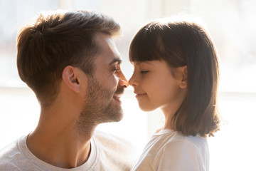 Happy loving father and kid daughter touching noses enjoy tenderness