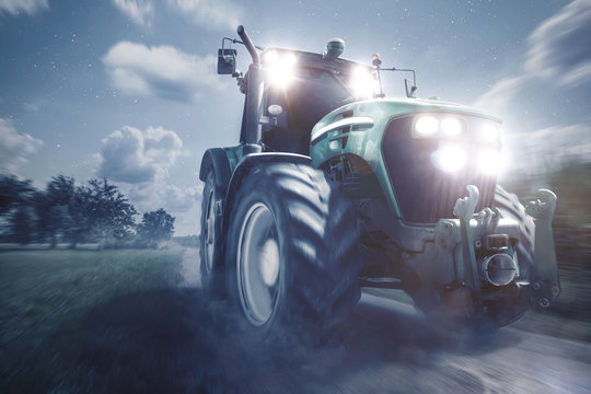 Traktor f&auml;hrt auf einem Feldweg bei Nacht
