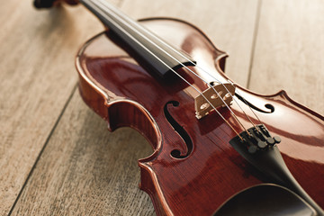 Fototapeta na wymiar Close up view of beautiful classical violin lying on wooden background. Music background