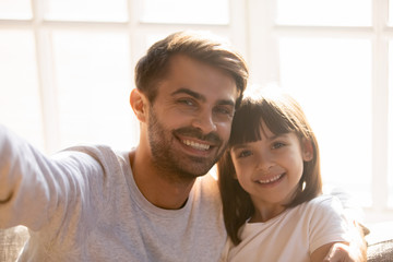 Fototapeta premium Dad and kid daughter with happy faces posing taking selfie