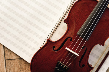 Naklejka premium Writing Violin Music. Close up view of beautiful brown violin lying on sheets for music notes. Musical instruments.