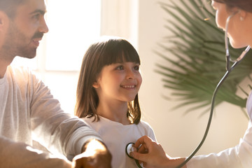 Female pediatrician holding stethoscope examining child visiting doctor with father