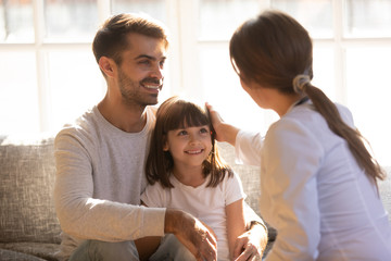 Caring doctor stroking head of child sitting on dads lap