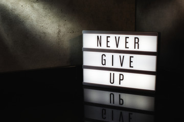Never give up motivational message on a light box in a cinematic moody background