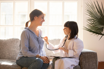 Obraz premium Cute girl as doctor playing with happy mom pretending nurse